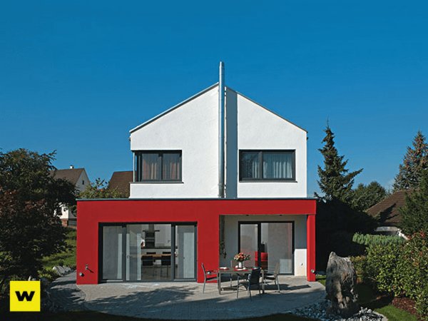 Modernes Einfamilienhaus mit roter Fassade, Flachdach und großer Terrasse im Garten.